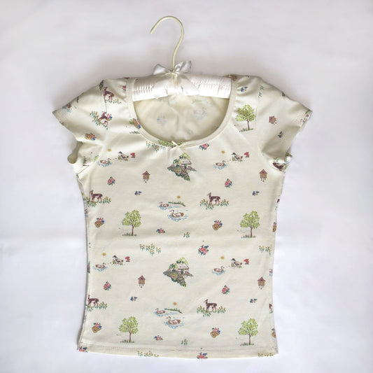a cream baby tee featuring a cottagecore print. has a cream bow along the scoop neckline.